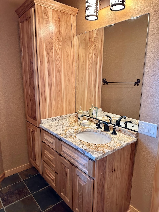 bathroom featuring baseboards, vanity, and a textured wall