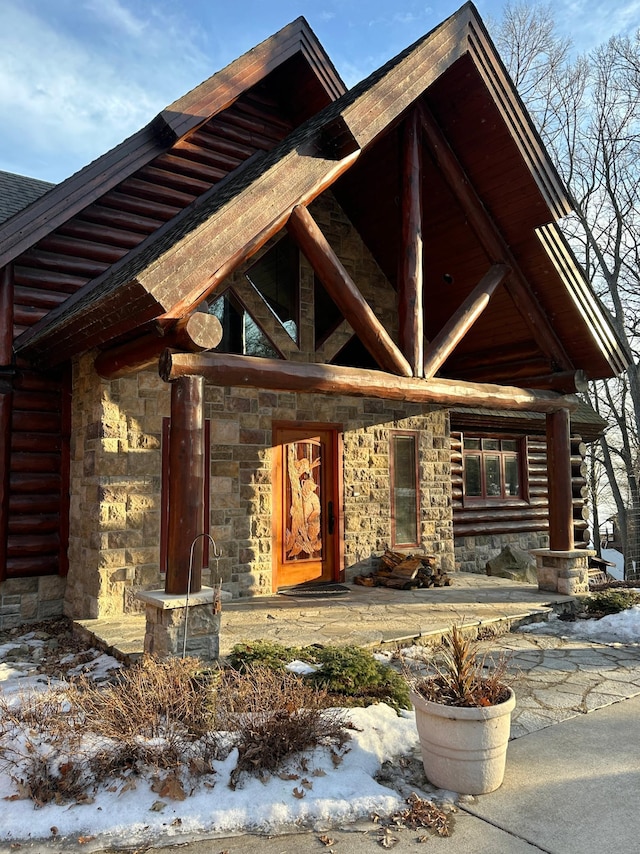 property entrance featuring log siding and stone siding