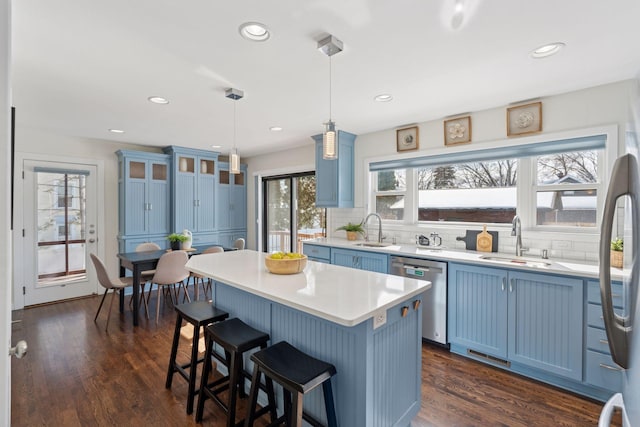 kitchen with a sink, backsplash, blue cabinets, and stainless steel dishwasher