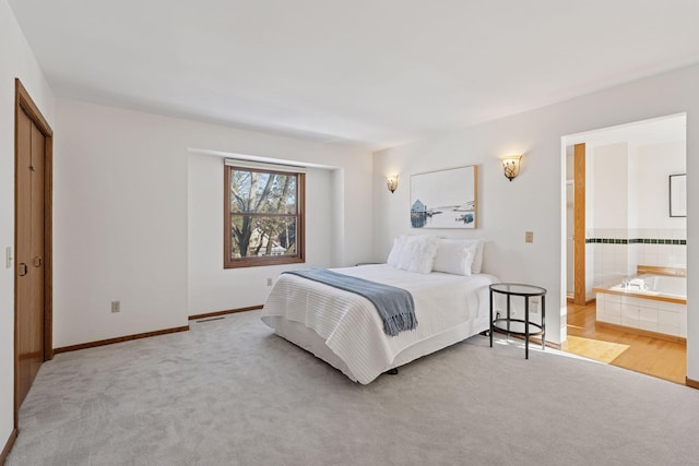 carpeted bedroom with connected bathroom and baseboards