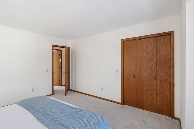 bedroom featuring baseboards, a closet, and light carpet