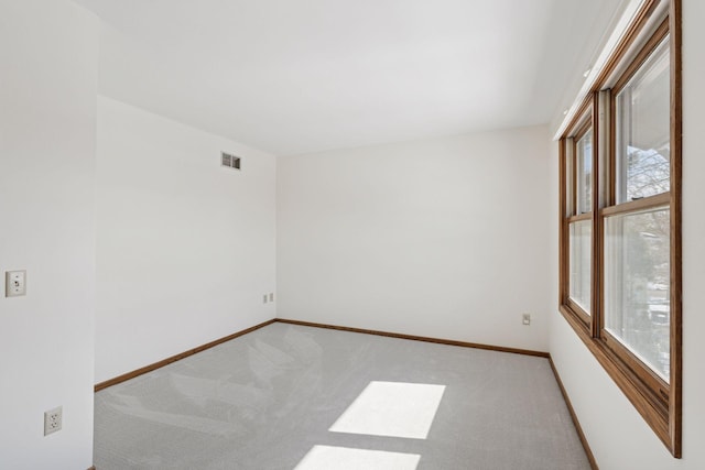 unfurnished room featuring baseboards, visible vents, and light carpet