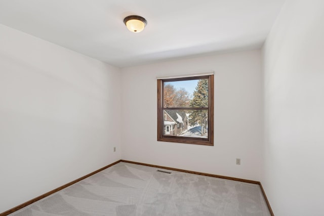 unfurnished room with visible vents, light colored carpet, and baseboards