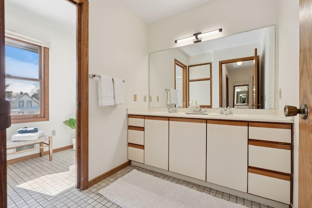 full bath featuring baseboards, double vanity, a sink, tile patterned floors, and toilet