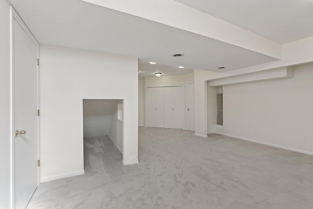 below grade area with baseboards, light carpet, and visible vents