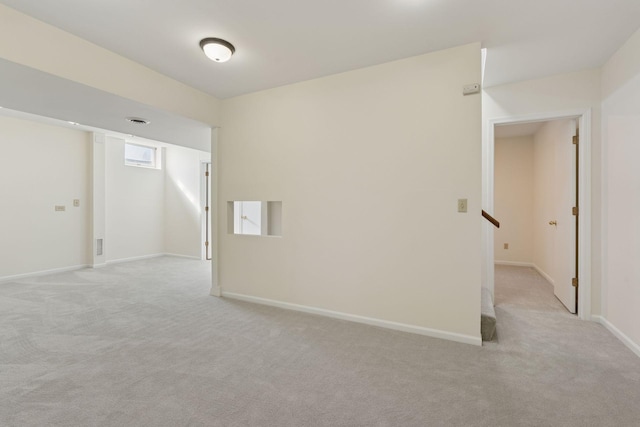 unfurnished room featuring light carpet, stairway, and baseboards