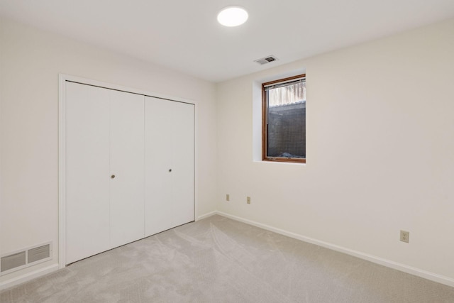 unfurnished bedroom with light carpet, visible vents, a closet, and baseboards