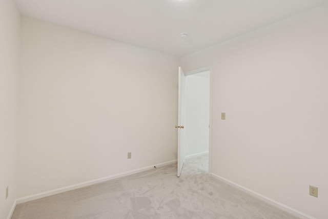 unfurnished room with baseboards and light colored carpet