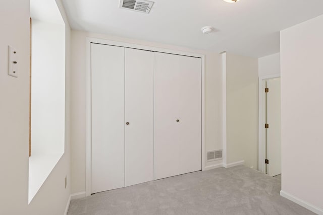 unfurnished bedroom with a closet, visible vents, and carpet floors