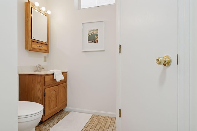 half bath featuring vanity, toilet, and baseboards