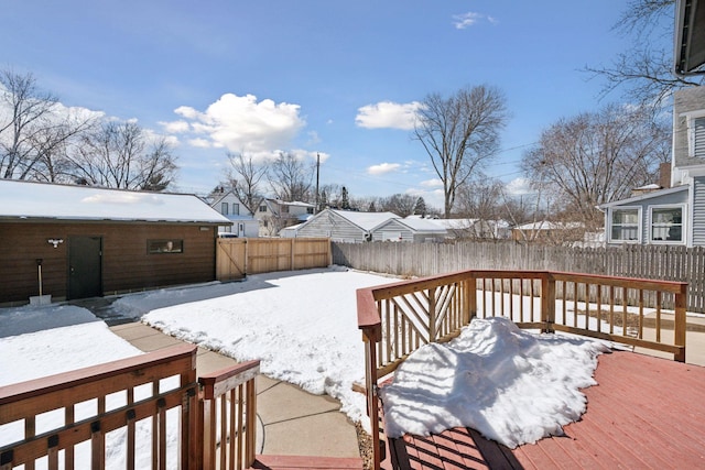 snowy yard featuring a residential view, a wooden deck, and a fenced backyard