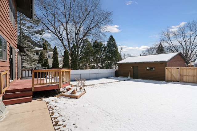 yard covered in snow featuring a deck, a gate, and a fenced backyard