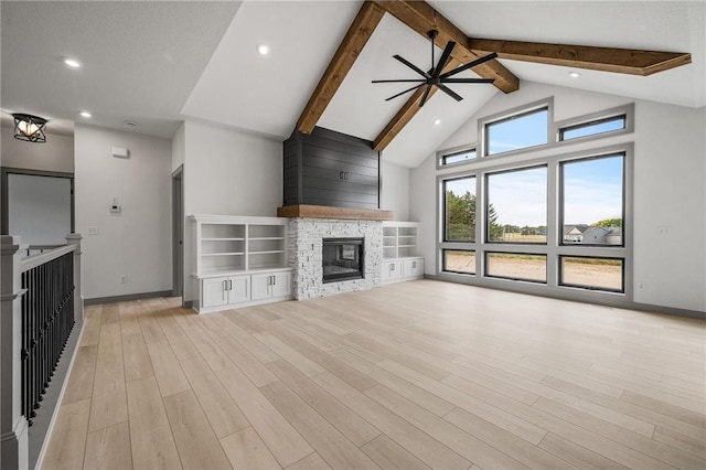 unfurnished living room with high vaulted ceiling, a fireplace, ceiling fan, light hardwood / wood-style floors, and beam ceiling