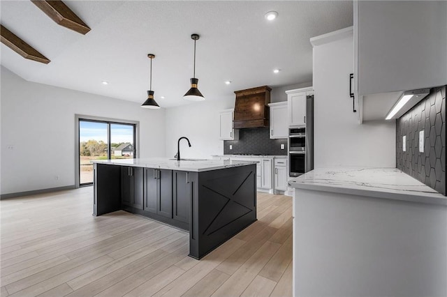 kitchen with premium range hood, double oven, hanging light fixtures, backsplash, and white cabinets