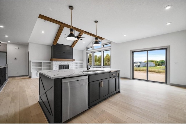 kitchen with light stone counters, lofted ceiling with beams, a center island with sink, stainless steel dishwasher, and a fireplace