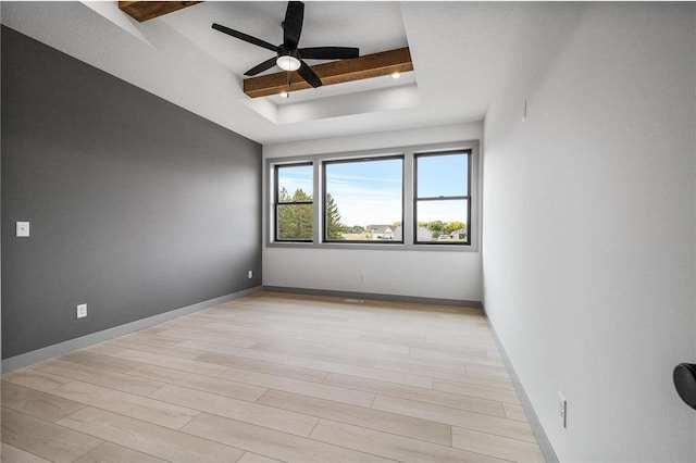 unfurnished room featuring ceiling fan, a tray ceiling, and light wood-type flooring