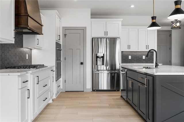 kitchen with sink, white cabinetry, hanging light fixtures, stainless steel appliances, and custom range hood