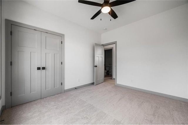 unfurnished bedroom featuring light colored carpet, ceiling fan, and a closet