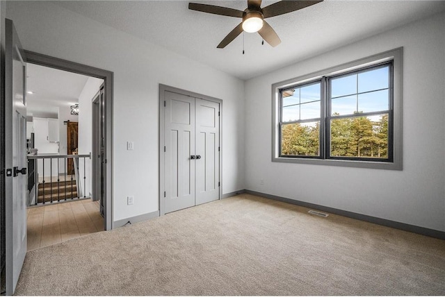 unfurnished bedroom featuring light colored carpet, a closet, and ceiling fan