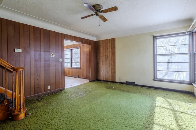 unfurnished room featuring a textured ceiling, carpet, and wood walls