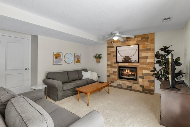 living room with ceiling fan, carpet floors, a textured ceiling, and a fireplace