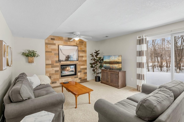 carpeted living room featuring ceiling fan, a large fireplace, and a textured ceiling