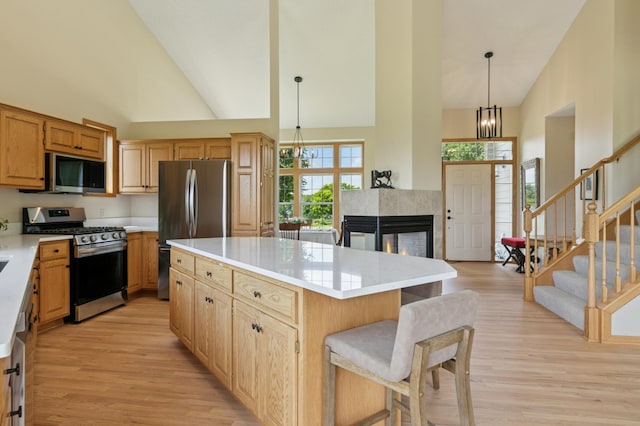 8051 165th St E, Credit River Twp, MN 55372 - kitchen featuring appliances with stainless steel finishes, high vaulted ceiling, light wood-style flooring, light countertops, and a center island