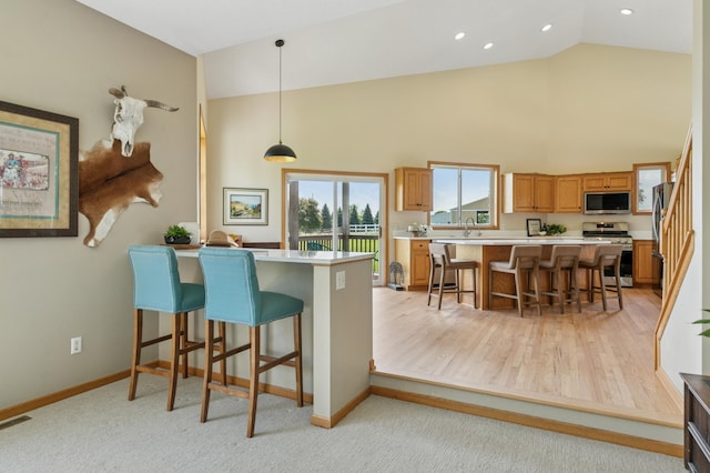 8051 165th St E, Credit River Twp, MN 55372 - kitchen with appliances with stainless steel finishes, light countertops, a kitchen bar, high vaulted ceiling, and brown cabinetry