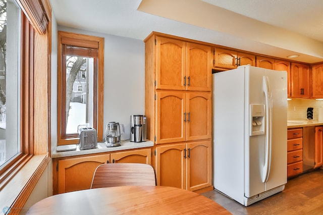 kitchen with tasteful backsplash, wood-type flooring, and white fridge with ice dispenser