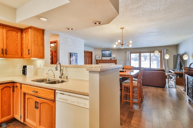 kitchen with sink, decorative light fixtures, white dishwasher, kitchen peninsula, and decorative backsplash