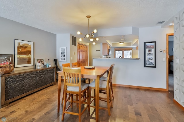 dining area featuring an inviting chandelier, wood-type flooring, and a textured ceiling