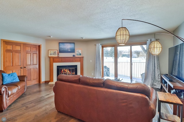 living room featuring wood-type flooring, a brick fireplace, and a textured ceiling