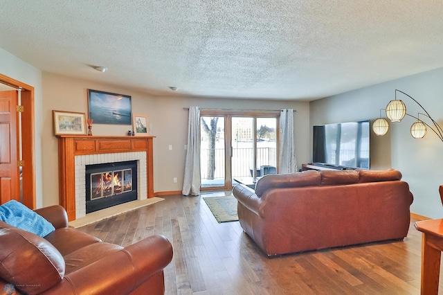 living room with wood-type flooring, a fireplace, and a textured ceiling