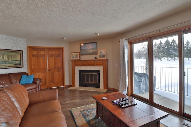 living room featuring hardwood / wood-style flooring, plenty of natural light, a fireplace, and a textured ceiling