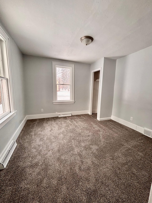 empty room featuring carpet flooring, a textured ceiling, and baseboard heating