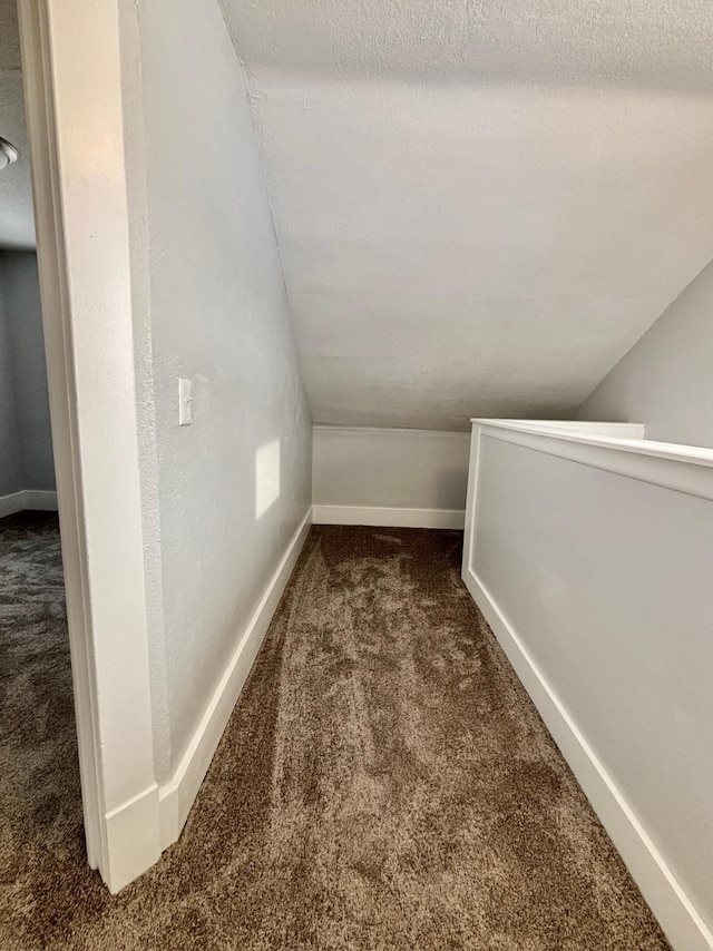 interior space with lofted ceiling and dark colored carpet