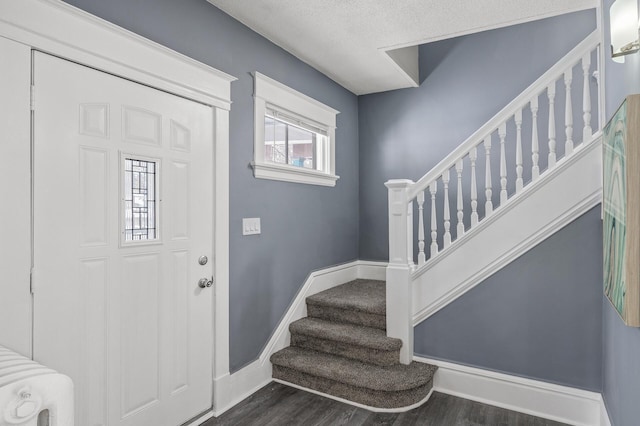 entryway with stairs, radiator heating unit, wood finished floors, and baseboards