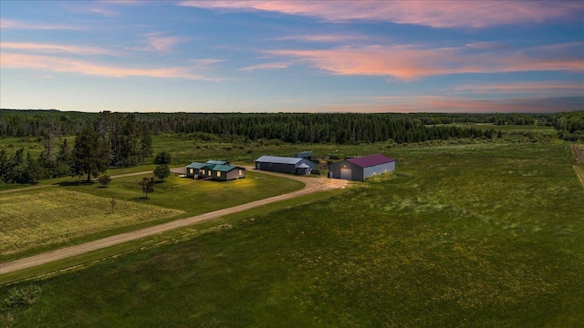 aerial view at dusk featuring a rural view and a view of trees