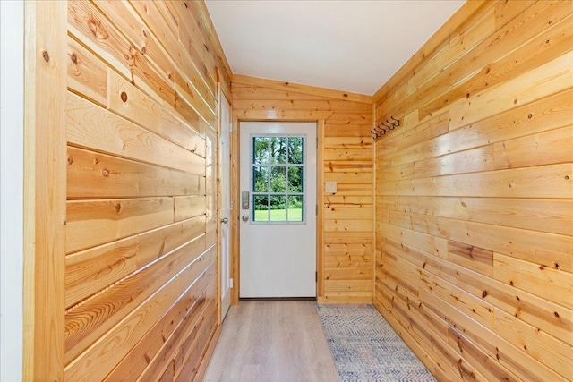 doorway with vaulted ceiling, wooden walls, and wood finished floors