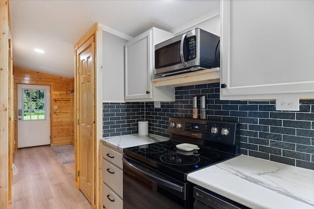 kitchen featuring stainless steel microwave, tasteful backsplash, black range with electric cooktop, and white cabinetry