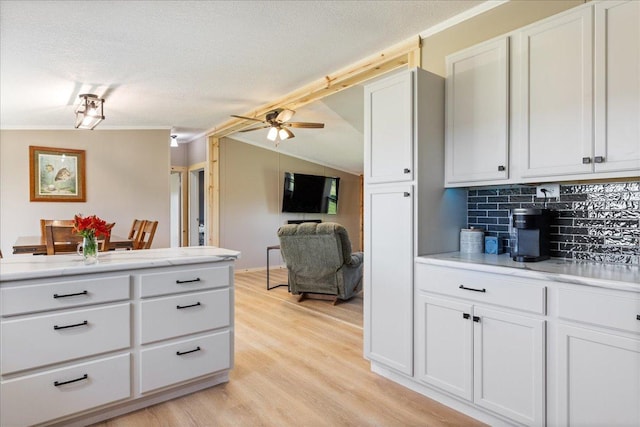 kitchen with light wood-type flooring, a textured ceiling, tasteful backsplash, light countertops, and lofted ceiling