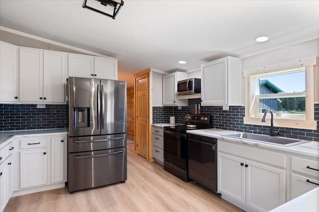 kitchen featuring black appliances, a sink, white cabinetry, light wood finished floors, and light countertops