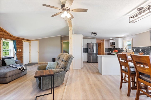 living area featuring light wood-style floors, a healthy amount of sunlight, and vaulted ceiling