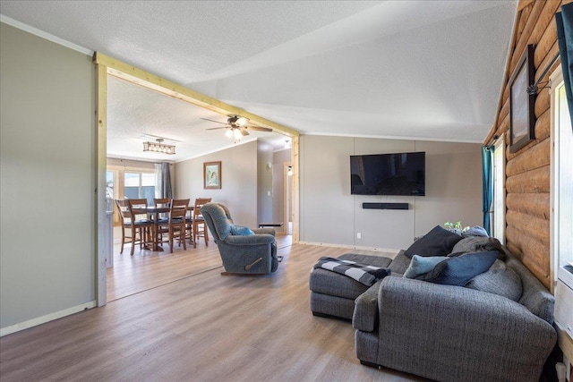 living area with lofted ceiling, a ceiling fan, a textured ceiling, wood finished floors, and baseboards