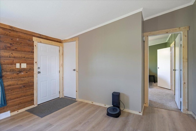 foyer entrance with baseboards, visible vents, crown molding, light wood-type flooring, and rustic walls