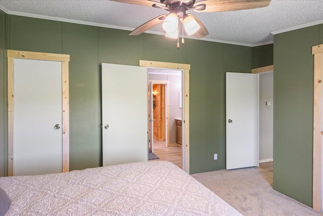 bedroom featuring ceiling fan, crown molding, light colored carpet, and a textured ceiling