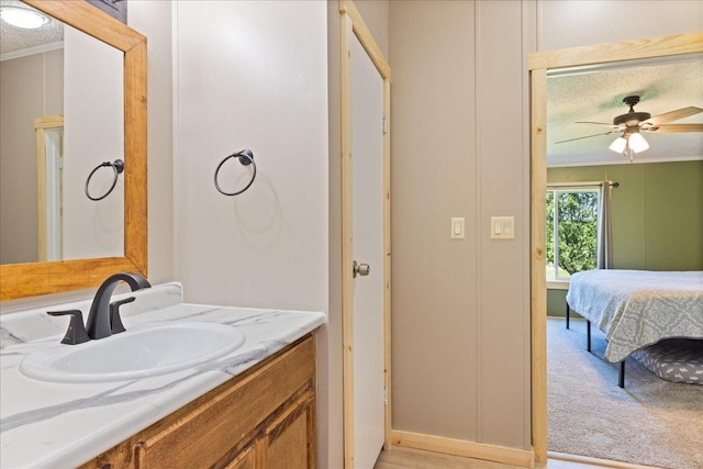 bathroom with connected bathroom, crown molding, ceiling fan, vanity, and a textured ceiling