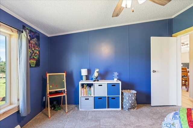 recreation room featuring ceiling fan, crown molding, carpet, and a textured ceiling