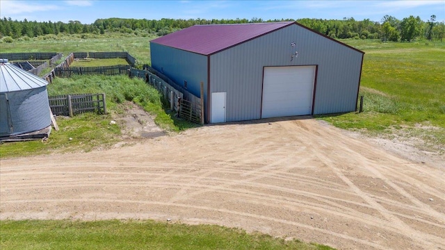 view of outbuilding featuring dirt driveway, an outdoor structure, and fence