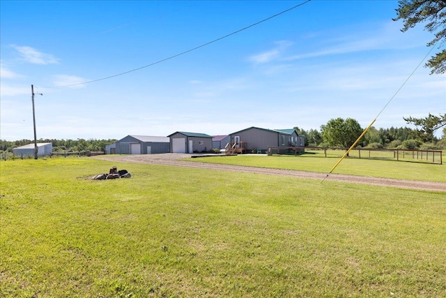 view of yard featuring a garage, a rural view, an outdoor structure, and driveway